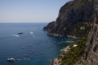 Panoramic view of Capri's coastline with cliffs, blue sea, and boats.