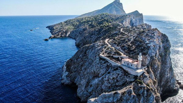 Aerial view of Punta Carena Lighthouse in Capri with cliffs and bright blue sea.