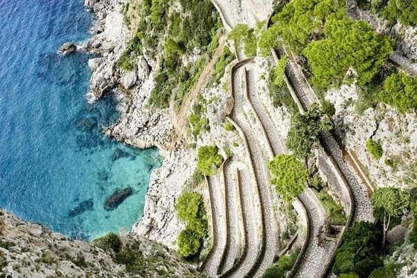 Vista aerea di Via Krupp a Capri con il mare turchese e la vegetazione lussureggiante.