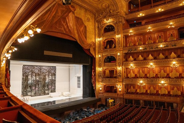 Interior of Teatro San Carlo in Naples, with illuminated stage and golden decor, set for a Christmas performance.