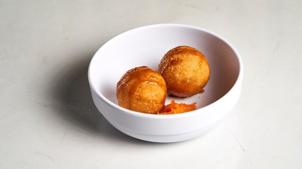 Two golden fried dough balls glazed in honey syrup, a classic Neapolitan Christmas sweet.