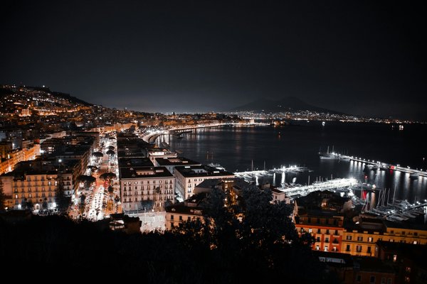 Night view of Lungomare Caracciolo in Naples with Mount Vesuvius in the background and Christmas lights along the coast.