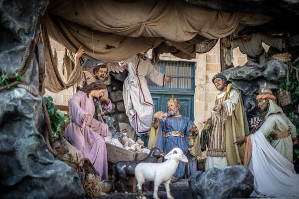 An elaborate life-sized nativity scene with the Holy Family, the Three Kings, and sheep, richly detailed and costumed.