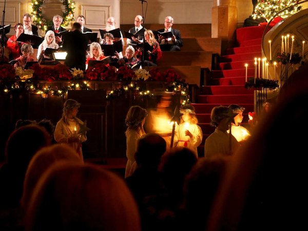 Christmas concert with choir and festive decorations, candles, and warm lights in a church.
