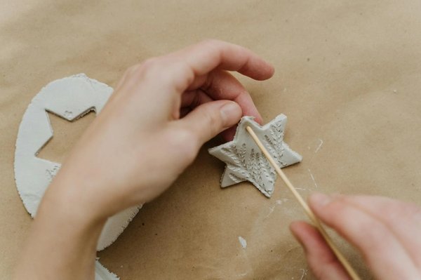 Hands crafting a star-shaped Christmas ornament in an artisan workshop.