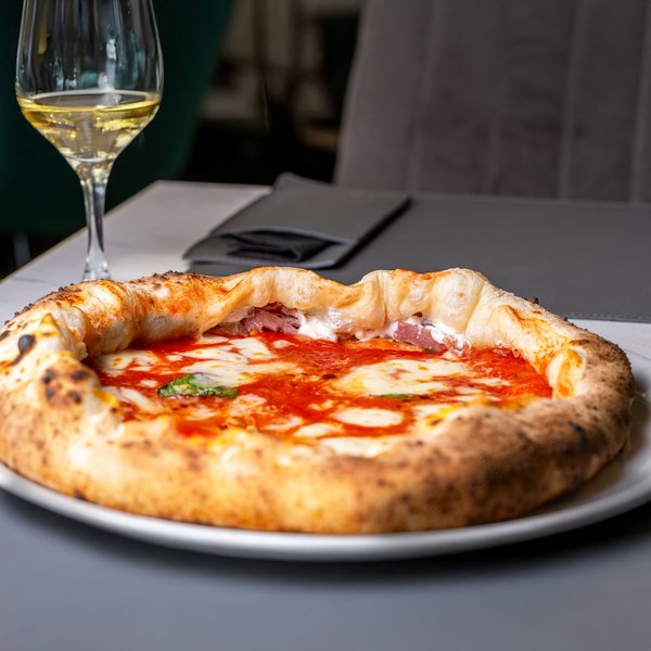 Neapolitan pizza with thick crust and glass of white wine on table, iconic representation of Naples cuisine.