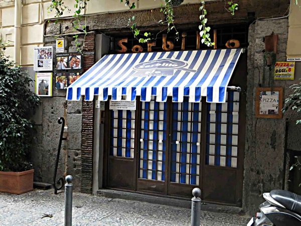 Entrance of Pizzeria Sorbillo in Naples with blue and white striped awning and outdoor decorations.