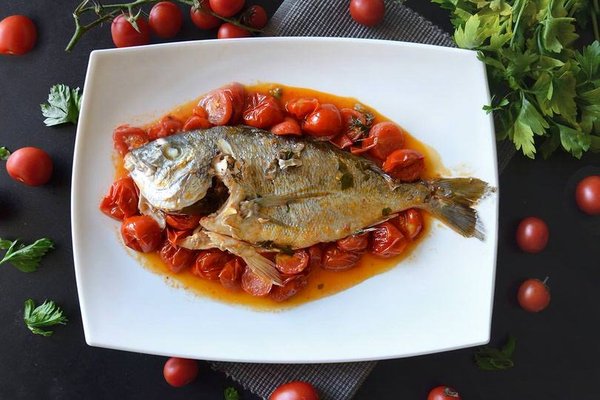 Fresh fish with cherry tomatoes on a white plate, traditional Neapolitan cuisine from Mimì alla Ferrovia.