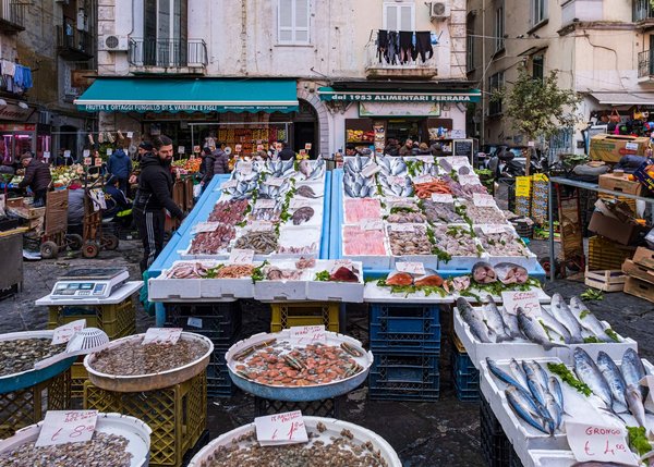 Fresh fish and seafood displayed at a bustling Neapolitan market stall.