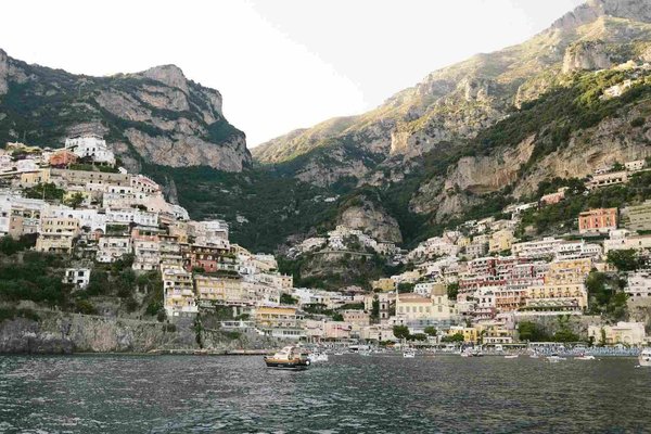 View of Positano with colorful houses on the cliff and boats on the water, taken from Spiaggia Grande beach.
