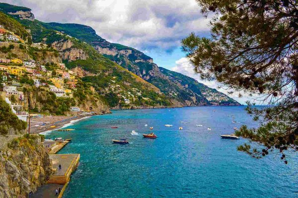 Panoramic view of Positano with colorful houses on the cliff and boats in the Mediterranean Sea.