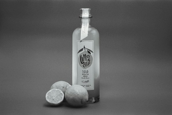 Bottiglia di limoncello con limoni freschi, simbolo iconico di Sorrento e della sua tradizione di produzione di limoncello.