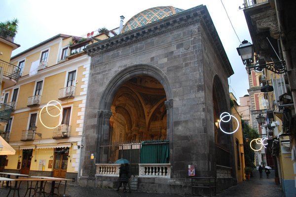 Sedile Dominova a Sorrento con dettagli architettonici e decorazioni, circondato da edifici storici e luci decorative.