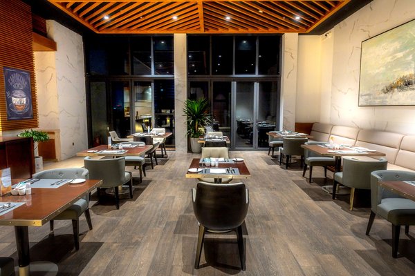 A spacious, contemporary restaurant dining room with clean lines and floor-to-ceiling windows.