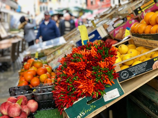 Crates of fresh oranges, lemons, and chili peppers displayed at an outdoor Italian produce market.