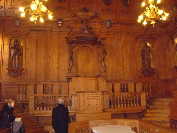 Anatomical Theatre of the Archiginnasio in Bologna with wooden details and statues, illuminated by chandeliers.