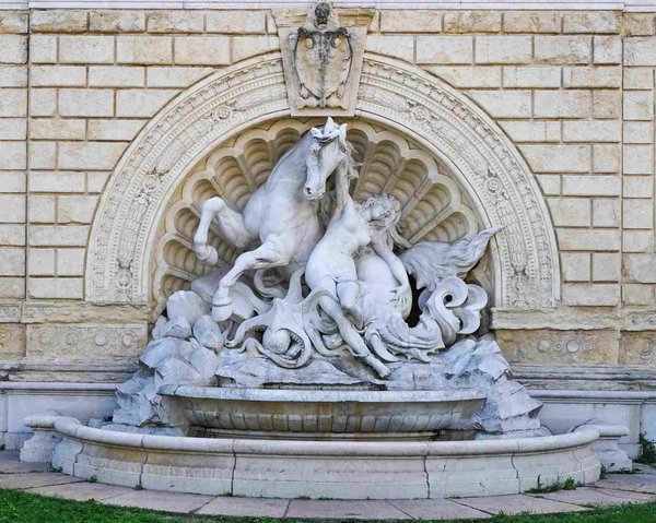 Decorative fountain in Montagnola Park in Bologna, featuring a marble horse and human figure sculpture.