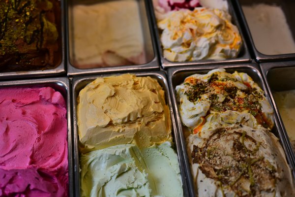 Tubs of colorful artisanal gelato including pistachio and fruit flavors.