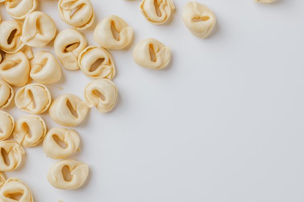Primo piano di tortellini freschi su sfondo bianco, specialità tipica di Bologna e del ristorante Trattoria Anna Maria.
