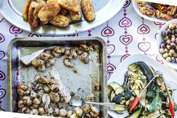 Spread of fried Italian antipasti including croquettes, roasted mushrooms, and grilled zucchini.