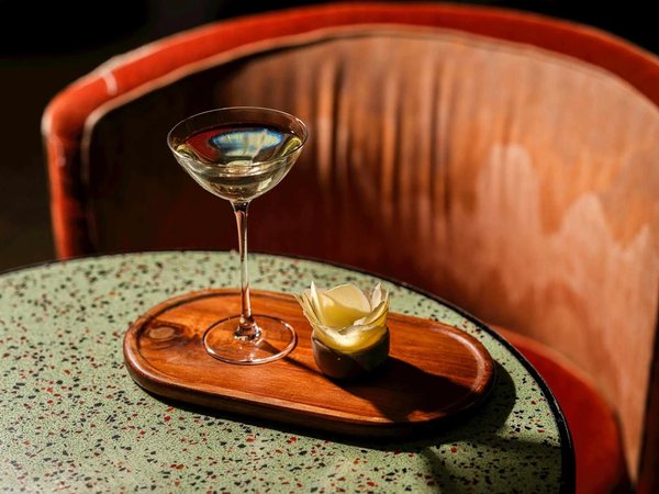 Elegant cocktail on a table with wooden decor and a background of a cushioned chair.