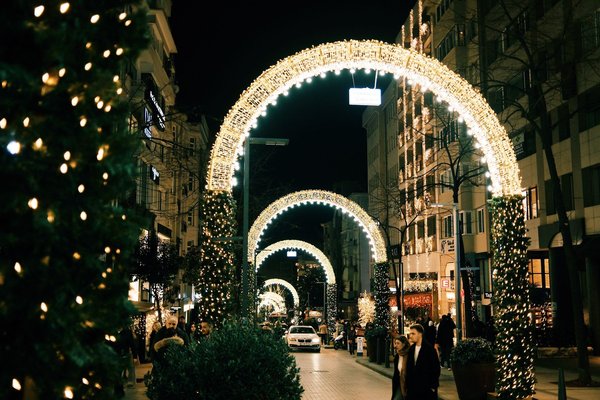 Arco illuminato di luci natalizie che attraversa una strada cittadina di notte.