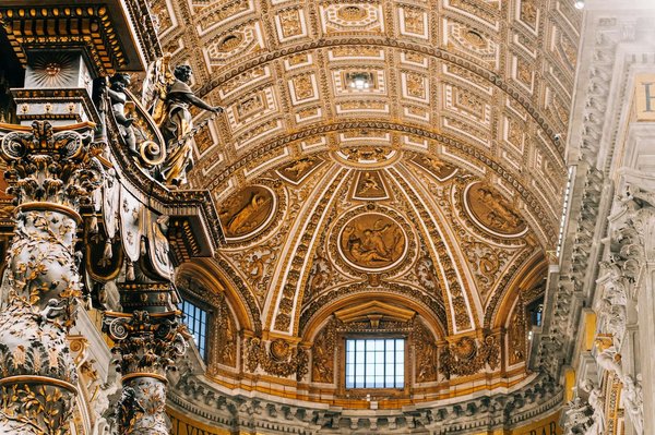 Interno della Basilica di San Pietro con le colonne del Baldacchino del Bernini e la volta dorata a cassettoni.