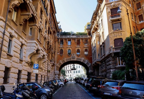 Lampadario in ferro battuto sospeso a un arco ornamentale che scavalca una strada nel Quartiere Coppedè di Roma.