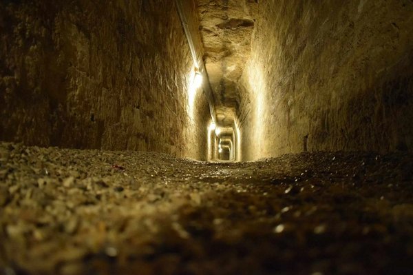 Tunnel sotterraneo con pareti in pietra e illuminazione soffusa nelle Catacombe di Priscilla a Roma.