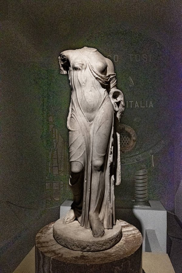 Statua romana in marmo esposta tra i macchinari industriali all'interno del museo della Centrale Montemartini a Roma.