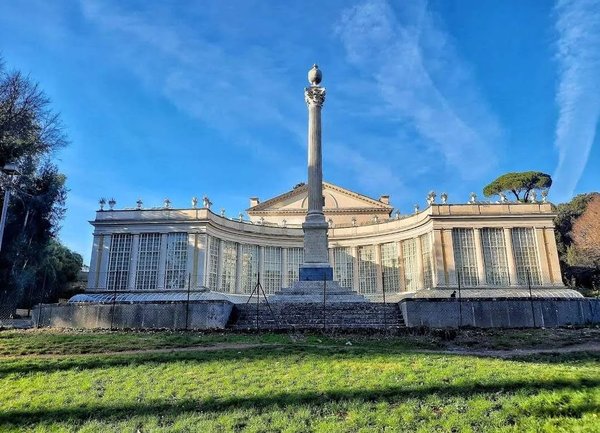 Facciata di Villa Torlonia a Roma con colonna centrale e cielo blu sullo sfondo.