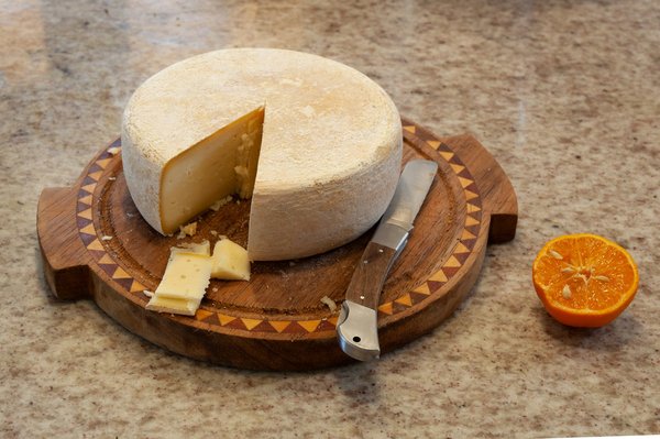 Forma di Pecorino Romano tagliata su un tagliere di legno.