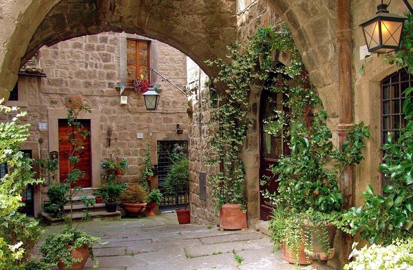 Arco medievale e cortile con piante e fiori nel Quartiere San Pellegrino a Viterbo.