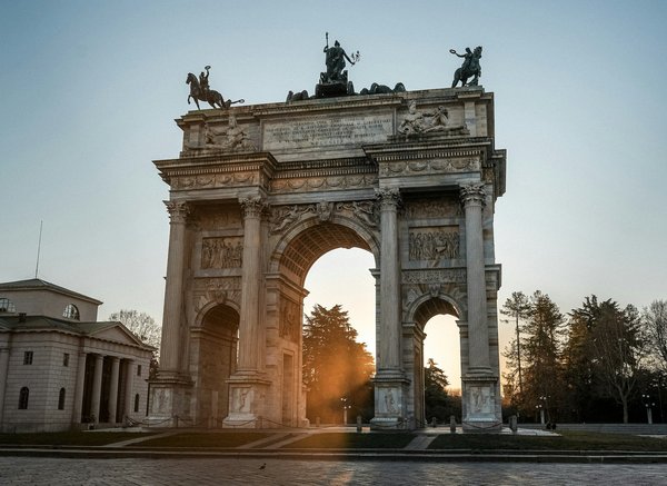 Arco della Pace al tramonto nel Parco Sempione, Milano, con luce calda e cielo limpido.