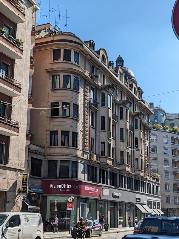 Historic building on Corso Buenos Aires in Milan with ground-floor storefronts and traffic below.