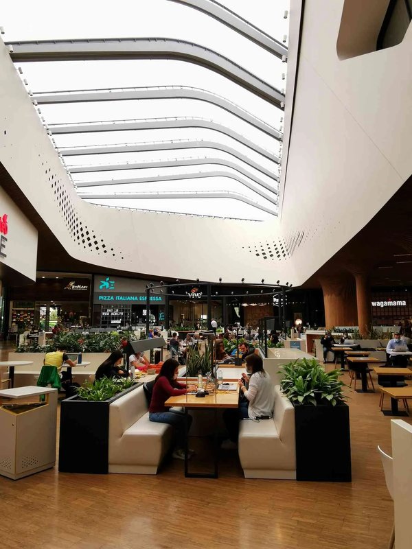 Interior of the CityLife Shopping District in Milan with a modern dining area and glass ceiling.