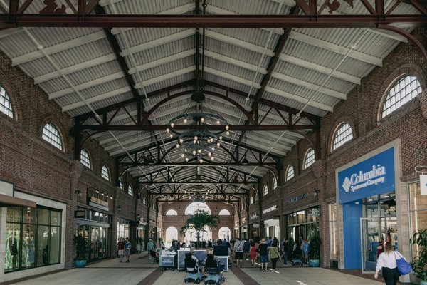Open-air outlet village with a brick colonnade and storefronts, including a Columbia Sportswear shop.