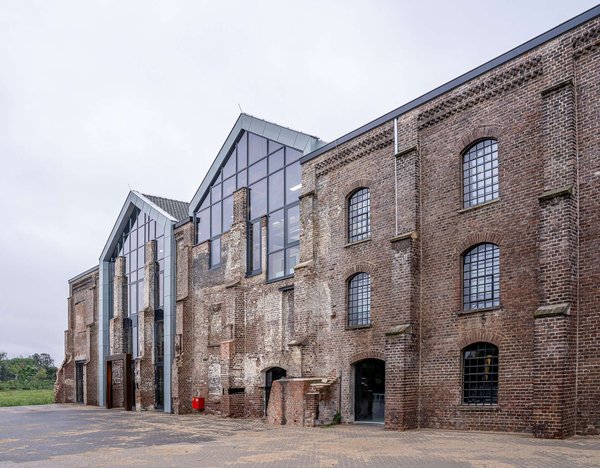 Converted industrial brick warehouse with large glass windows, typical of Isola's design studios.