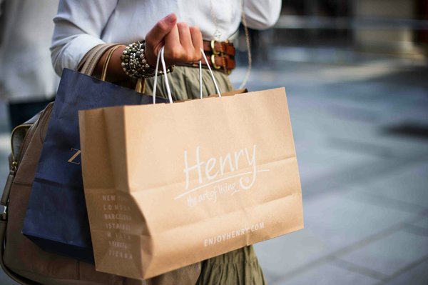 Close-up of a shopper carrying paper shopping bags from a boutique.