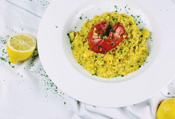 Golden saffron risotto plated elegantly with a lobster tail garnish.