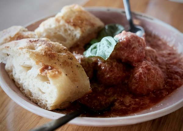 Meatballs in tomato sauce with basil, served with rustic bread.