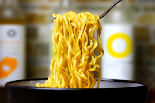 Fresh egg noodles lifted with a fork from a bowl, hand-pulled Chinese noodle style.