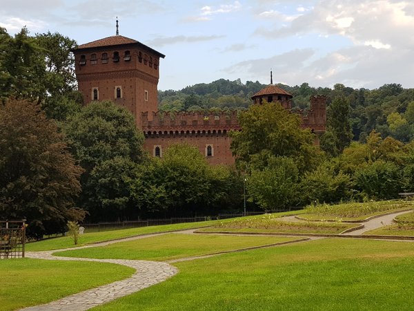 La Rocca del Borgo Medievale nel Parco del Valentino a Torino, circondata da prati e alberi.