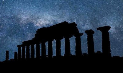 Silhouette di un tempio greco antico nella Valle dei Templi ad Agrigento, Sicilia, con un cielo stellato sullo sfondo.