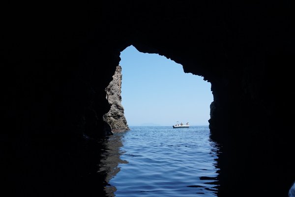 View of a sea cave with a boat on the water near the Aeolian Islands, Alicudi and Filicudi.
