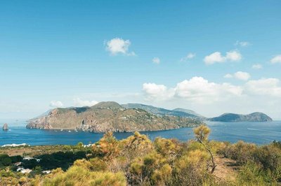 Panoramic view of the Aeolian Islands with rocky coast, blue sea, and Mediterranean vegetation.