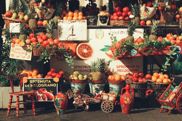 Local market with fresh fruit, pineapples, pomegranates, and colorful Sicilian decorations, perfect for exploring Aeolian Islands.