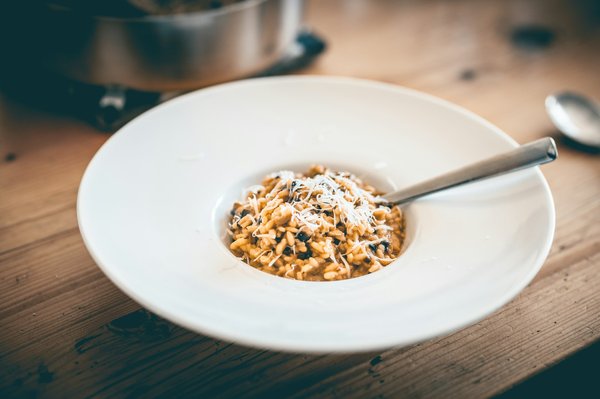 Porcini mushroom risotto topped with grated Parmesan in a white bowl.