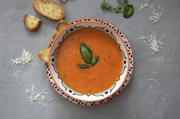 Bowl of pappa al pomodoro tomato-bread soup garnished with basil and toasted bread.