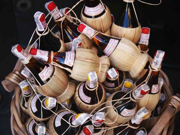 Basket of traditional Chianti wine bottles with straw coverings, symbolizing Florence's food and wine culture.